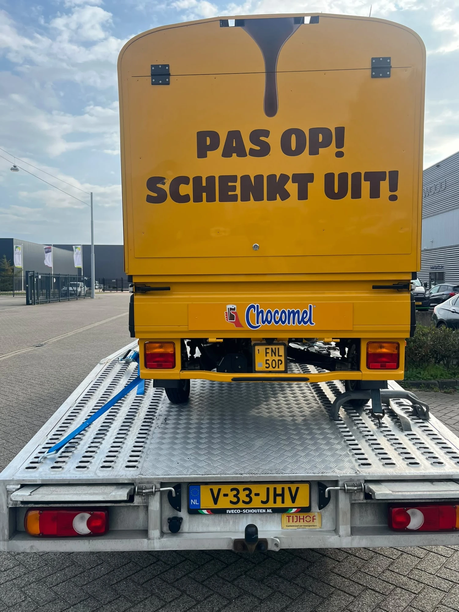 Achterkant van de Chocomel-wagen met de tekst Pas op schenkt uit, vastgezet op de oprijwagen
